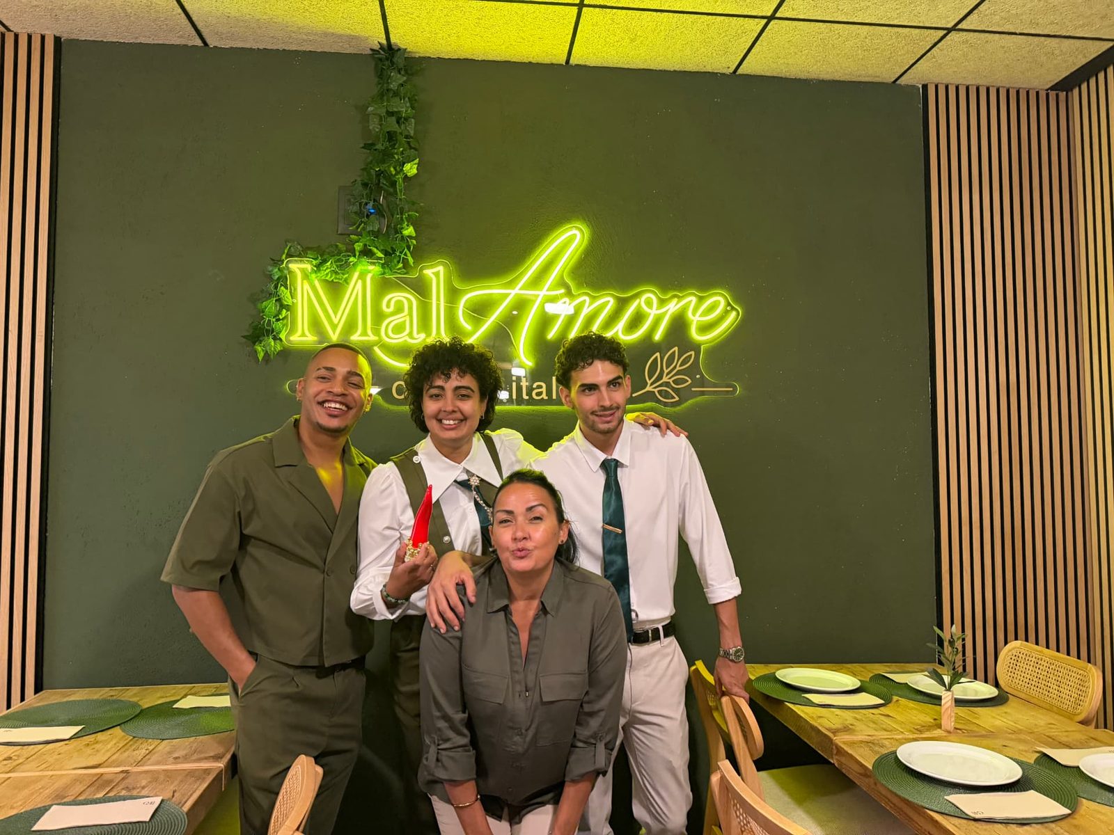 El equipo de MalAmore junto al rótulo luminoso en la noche de la inauguración