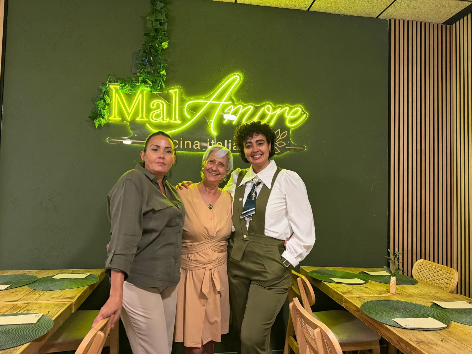 Tres personas del equipo posando ante el rótulo de MalAmore